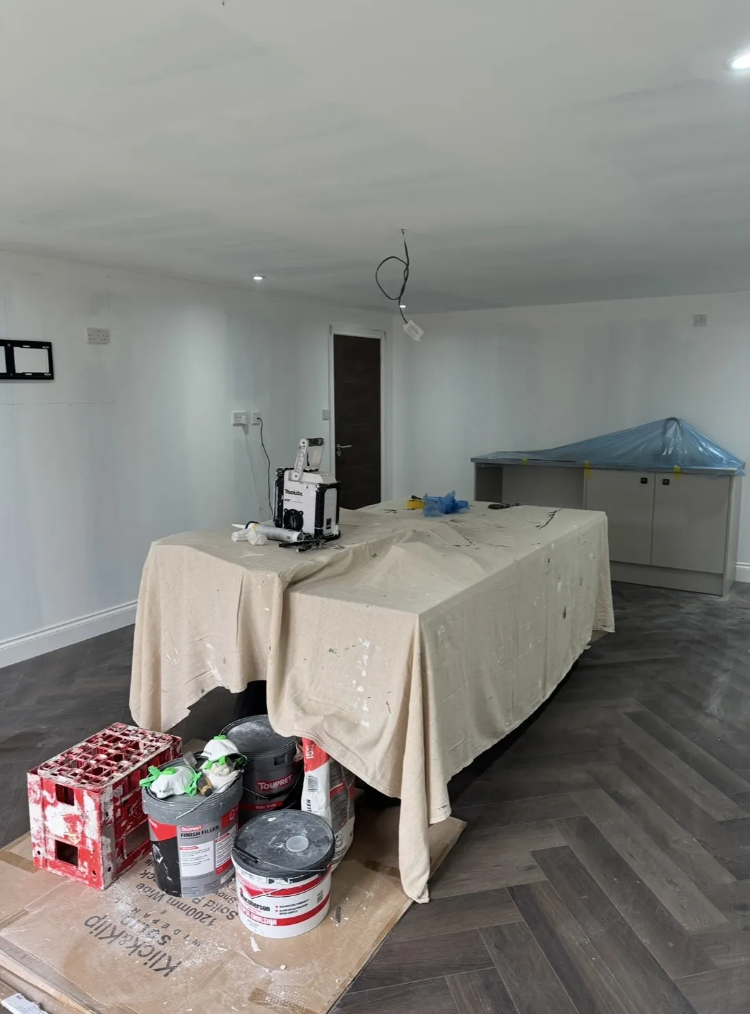 Large room with covered furniture ready for painting