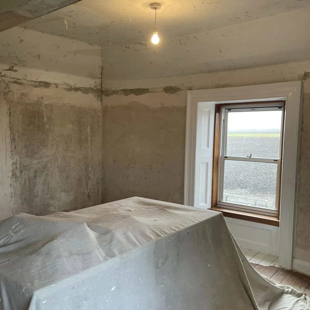 Before Image of an old room with wallpaper and old paint stripped off it