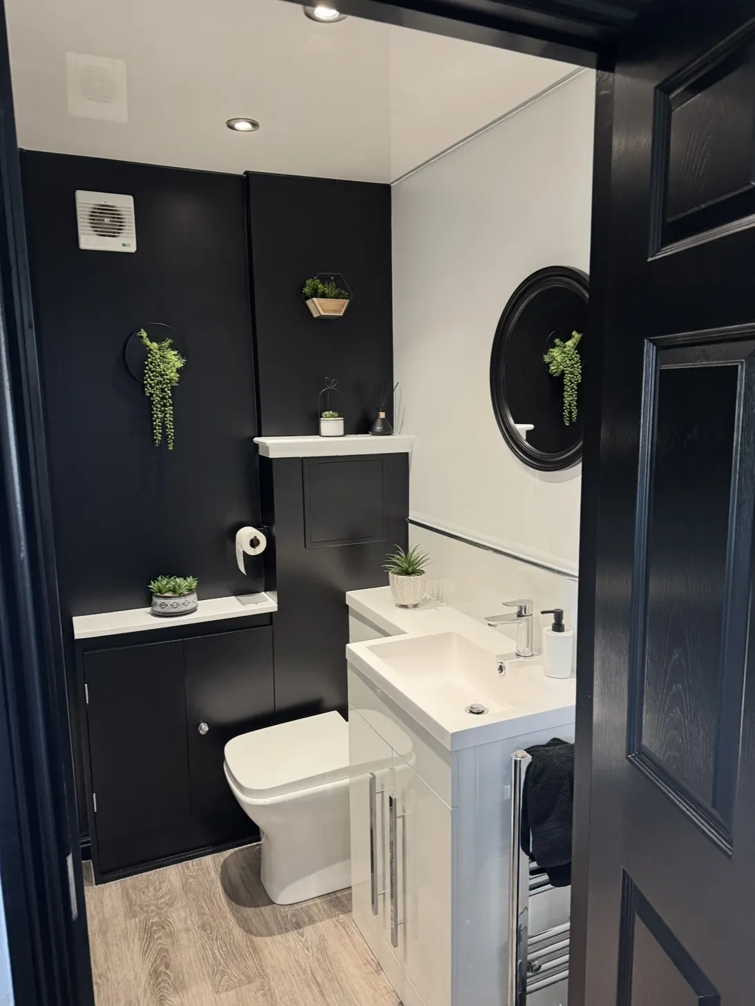 Modern and minimalistic bathroom painted in a monochrome colour scheme with some green accents from the plants
